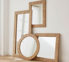 three mirrors sitting next to each other on top of a hard wood floor in front of a white wall