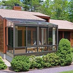 a house with an enclosed porch and covered patio area in the middle of a wooded area