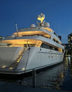 a large white boat is docked in the water at night with lights on it's side