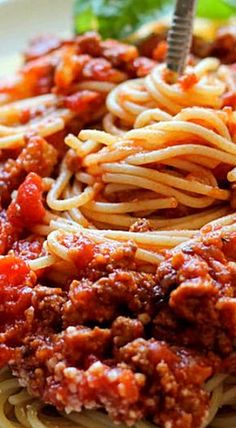 spaghetti with meat sauce and spinach leaves on the side, ready to be eaten