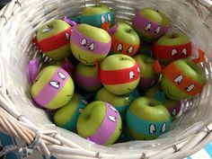 a basket filled with lots of green apples covered in teenage mutant ninja turtles painted on them