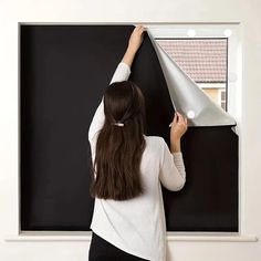 a woman standing in front of a blackboard with a white cone on it