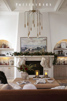 a living room decorated for christmas with stockings and candles on the fireplace mantels