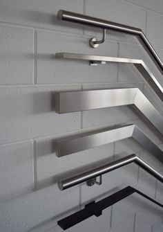 three metal shelves on the side of a white brick wall with bars attached to them