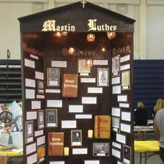 a display case with pictures and information on the wall in front of people sitting at tables