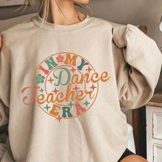 "PLEASE READ ENTIRE DESCRIPTION BEFORE ORDERING Unisex Fit Dance Teacher Sweatshirt, Funny Dancer Shirt, Choreography Sweatshirt, ballet teacher Sweatshirt, dance teacher Crewneck, Oversized, Unisex Fall in love with this soft and cozy Graphic Tee, Sweatshirt or hoodie  TO MAKE YOUR SHOPPING EXPERIENCE EASIER, YOU CAN \"CHOOSE\" A T SHIRT, SWEATSHIRT OR HOODIE IN THIS LISTING. Size up 1-2 sizes for a slouchy oversized fit PINK, Sand and light blue are NOT available in a 4X 5X Sweatshirt but they ARE  available in Tshirt Youth Kids Shirts, unisex Tshirt and Sweatshirt Available! DTG PRINTING Sweatshirt and Hoodies Sizes: S M L XL 2X 3X 4X 5X Handmade  Unisex Fit Crewneck Sweatshirts 50/50 cotton polyester  Long Sleeve TEES 100% Cotton Sizes:  Youth Tee: XS-XL Unisex Tees: S-5X *TRUE TO SIZE Casual Letter Print Sweatshirt For Dance, Crew Neck Sweatshirt With Letter Print For Dance, Long Sleeve Letter Print T-shirt For Dance, Long Sleeve T-shirt With Letter Print For Dance, Graphic Print Crew Neck Sweatshirt For Dance, Long Sleeve Graphic T-shirt For Dance, Casual Crew Neck Top For Dance, Long Sleeve Graphic Print T-shirt For Dance, Cotton Tops For Dance Class In Fall