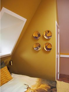 three mirrors mounted to the side of a wall above a bed in a room with yellow walls