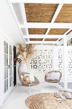 two wicker chairs sitting on top of a white floor next to a potted plant