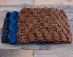 three knitted blankets sitting on top of a wooden floor