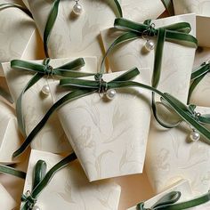 many white boxes with green ribbons tied around them and some pearls on the top one