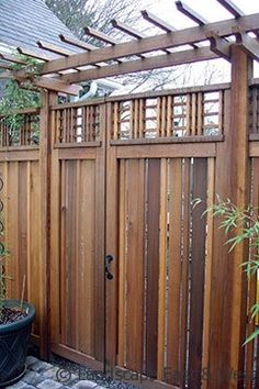 a wooden fence with a potted plant next to it and an arbor in the background