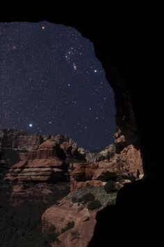 the stars are shining brightly in the sky above some rocks and trees at night time