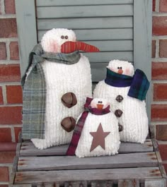 two snowmen sitting on top of a wooden bench