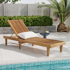 a wooden chaise lounge chair next to a swimming pool with a bowl of fruit on it