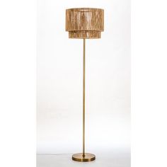 a floor lamp with a beige shade on the base and a gold colored metal pole