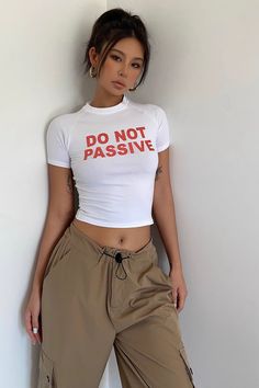 a woman leaning against a wall with her hands on her hips wearing cargo pants and a t - shirt that says do not passivve