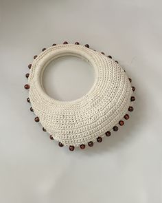 a white crocheted bag with brown beads on it