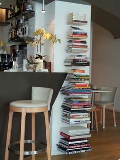 there is a tall stack of books on the counter in front of this bar with two stools