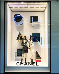 two mannequins dressed in black and white clothing stand behind a window display