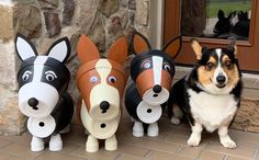 a dog is sitting next to three dogs made out of toilet paper and plastic cups