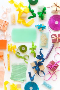 many different types of crafting supplies laid out on a white surface with ribbons, scissors and other items