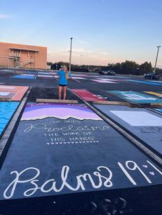 a woman standing in the middle of a parking lot next to a chalkboard sign