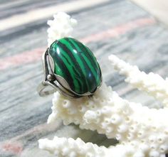 Vintage fashion jewelry, Malachite imitation woman's ring in size 9.Only 1 item available, not adjustable and not resizeable. Very good condition.Size: 9 ( US and Canada ), R 3/4 ( UK and Australia ), 19 ( Europe ).Stone: stripy green MAlachite imitation ( AKA pressed stone or reconstituted malachite )The stone is oval shape, measuring 14X10 mm and standing 7 mm tall over the finger surface.Material: Silver plated brass.This is a high quality ring in electric silver plate with 980 silver that la Adjustable Green Malachite Jewelry, Adjustable Fit Emerald Ring, Adjustable Turquoise Gemstone Ring, Adjustable Green Turquoise Gemstone Ring, Green Malachite Rings As A Gift, Vintage Green Turquoise Cabochon Ring, Formal Green Malachite Jewelry, Unique Green Jewelry For Formal Occasions, Handmade Adjustable Green Emerald Ring