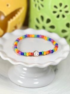 Everyone can use a little dose of happy and, to be honest, it’s hard not to smile back at these cute little stretch bracelets. Need a little mood boost? Just glance at your wrist! Glass beads frame a single enamel in metal smiley face. She measures about 7 inches around. If you need a different length, please just let us know. Cheerful Adjustable Friendship Bracelets As Gift, Adjustable Rainbow Beaded Bracelets Playful Style, Adjustable Rainbow Beaded Bracelets, Playful Style, Cheerful Adjustable Multicolor Friendship Bracelets, Adjustable Rainbow Beaded Bracelets In Playful Style, Fun Adjustable Nickel-free Bracelets, Fun Multicolor Stretch Bracelet For Everyday, Fun Rainbow Friendship Bracelets As Gifts, Cheerful Multicolor Adjustable Friendship Bracelets