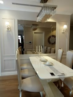 a dining room table with white chairs and a chandelier