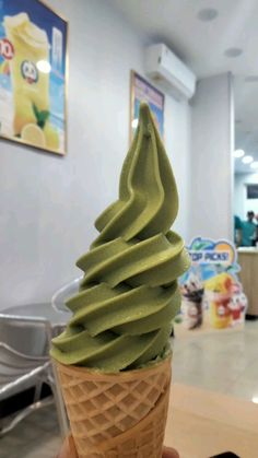 a hand holding an ice cream cone filled with green liquid