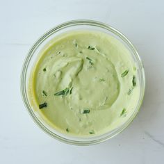 a glass bowl filled with green sauce on top of a white counter