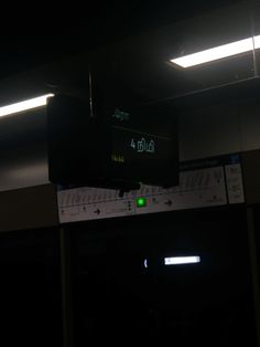 an electronic clock hanging from the ceiling in a dark room