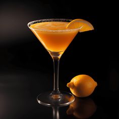 an orange cocktail garnished with a slice of lemon on a black table top