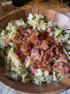 a wooden bowl filled with pasta salad and bacon