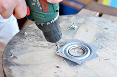 a person using a drill to fix a hole in a piece of wood on top of a table