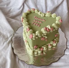 a green heart shaped cake with pink flowers on the bottom and writing happy birthday 1970