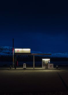 an empty gas station at night with mountains in the background