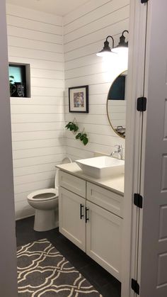 a bathroom with a toilet, sink and mirror next to a doorway leading into another room