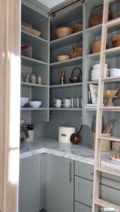 a ladder is in the middle of a kitchen with gray cabinets and white counter tops