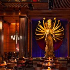 a large golden statue in the middle of a restaurant with tables and chairs around it