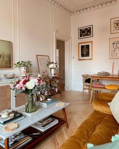 a living room filled with lots of furniture and flowers on top of a coffee table