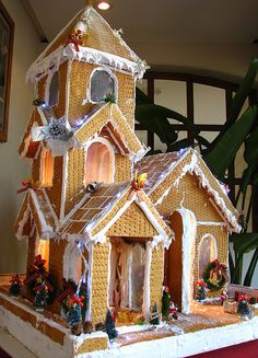 a gingerbread house is decorated with icing and lights on the front, while other decorations are around it