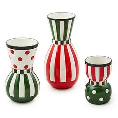 three different colored vases sitting next to each other on a white surface with polka dots