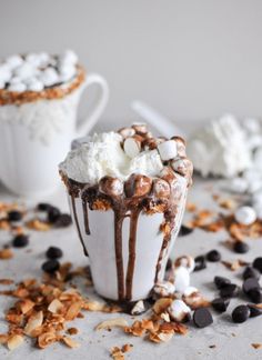 two cups filled with hot chocolate and marshmallows on top of a table