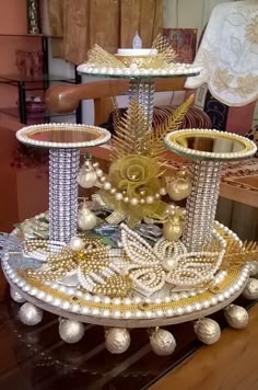 a three tiered tray with gold and white decorations on it, sitting on top of a wooden table