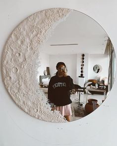 a woman standing in front of a mirror with the moon on it's side