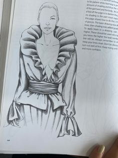 a person holding up a book with an image of a woman in a dress