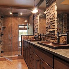 a large bathroom with stone walls and double sinks on the counter, along with a walk in shower