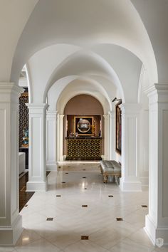 an arched hallway with benches and paintings on the wall, along with marble flooring