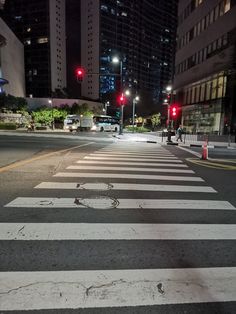 an empty city street at night with red traffic lights and buildings in the back ground